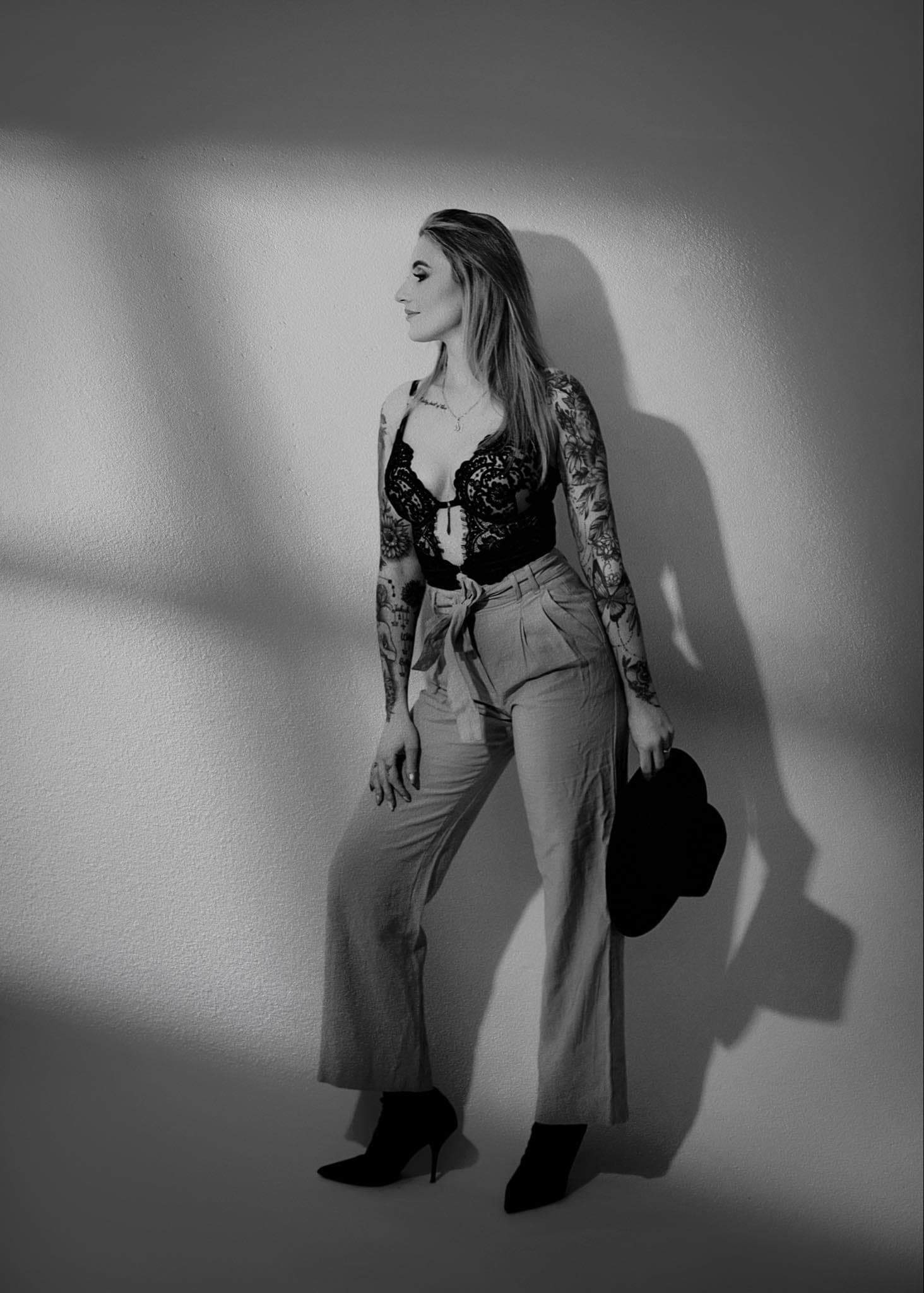 Karolina Gosz in a monochrome editorial portrait shaped by dramatic wall shadow, quiet tension and tailored styling