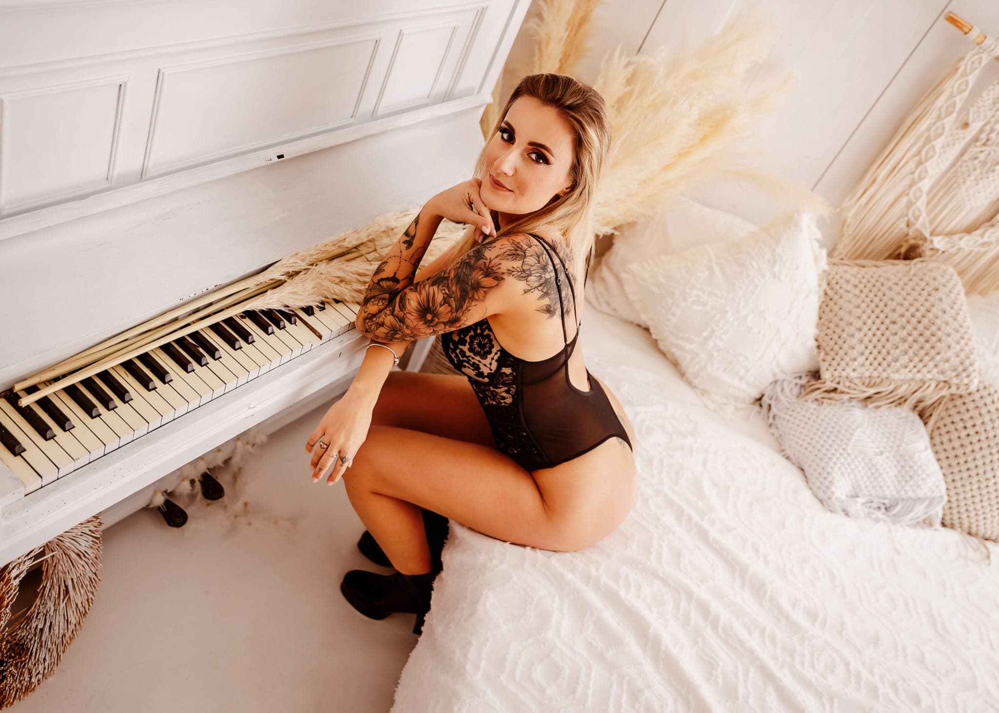 Karolina Gosz in an ivory studio scene beside a white piano, framed with soft highlights and calm editorial poise