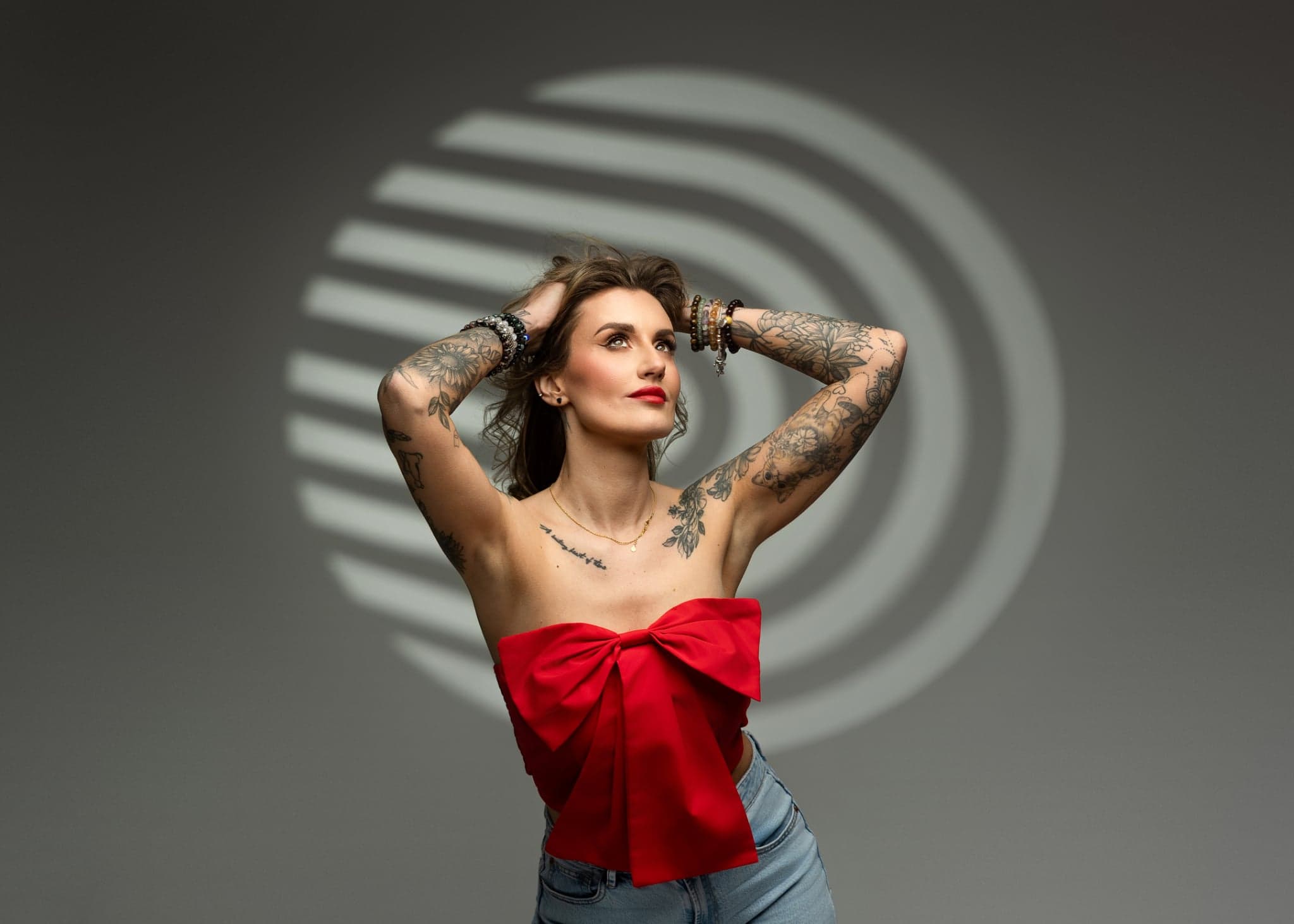 Karolina Gosz in a studio fashion portrait with red bow styling, diffused light and a muted grey backdrop